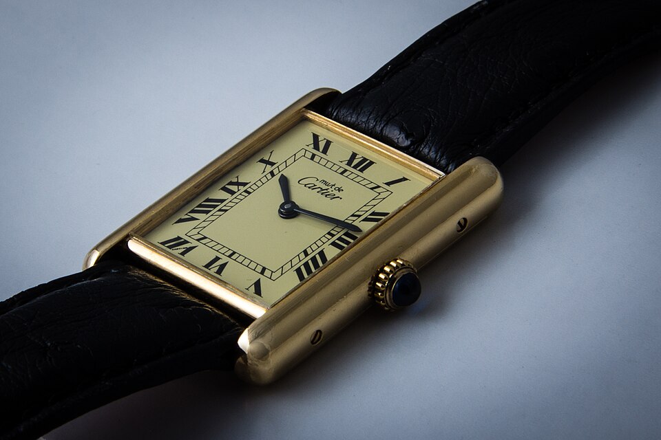 A Must de Cartier Tank with a gold-colored rectangular case, Roman-numeral dial and dark leather strap.