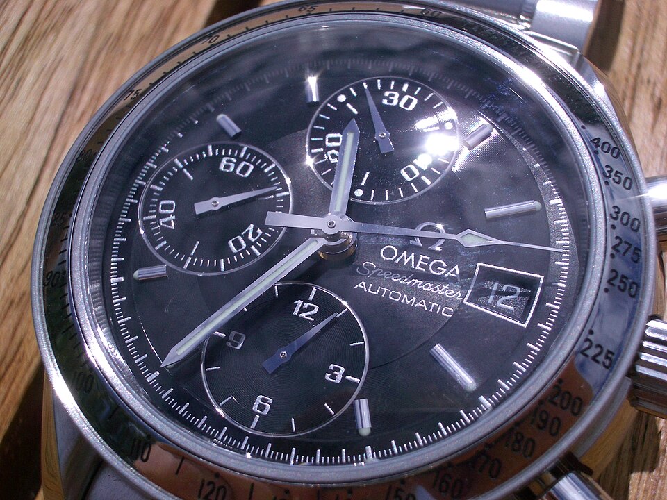 Close-up of an Omega Speedmaster Automatic with three subdials, a date window and a tachymeter bezel.