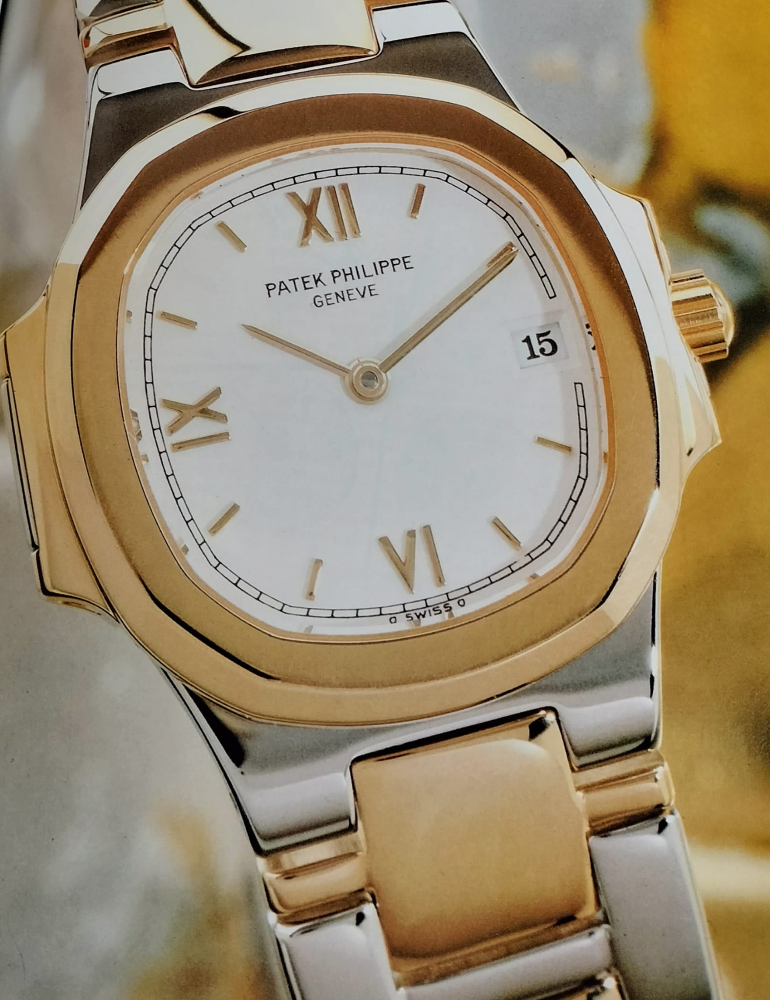 Close-up of a two-tone Patek Philippe Nautilus with a light dial and date window.